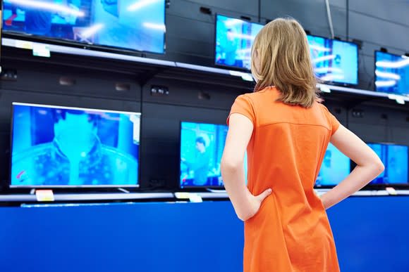 Woman standing in front of TVs in a store.