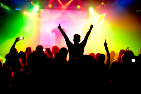 silhouettes of concert crowd in front of bright stage lights