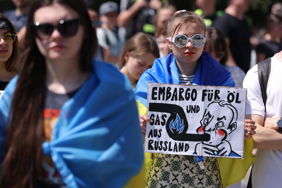 A young woman holds a sign urging an embargo on Russian oil and gas during a protest gathering to demand Europe keep its promises towards supporting Ukraine on 5 June 2022 in Berlin, Germany (Getty Images)