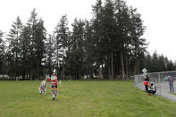 In this photo taken Saturday, April 4, 2020, Wakiyan Cuny, left, and his sister Wicahpi Cuny, Dakota and Lakota tribal members, are filmed by their mother Tera Baker during a live streamed powwow from a park near their home, in Puyallup, Wash. The largest powwows in the country have been canceled or postponed amid the spread of the coronavirus. Tribal members have found a new outlet online with the Social Distance Powwow. They're sharing videos of colorful displays of culture and tradition that are at their essence meant to uplift people during difficult times. (AP Photo/Elaine Thompson)