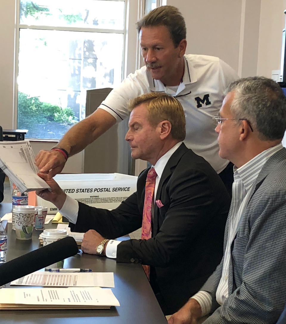 Brad Sinnott, center, and Doug Priesse, both Republican members of the bipartisan Franklin County Board of Elections in Columbus, Ohio, examine ballots in an uncalled special congressional election on Friday, Aug. 24, 2018. Republican state Sen. Troy Balderson, of Zanesville, led Democrat Danny O'Connor, the Franklin County recorder, ended the Aug. 7 election separated by less than a percentage point. (AP Photo/Julie Carr Smyth)