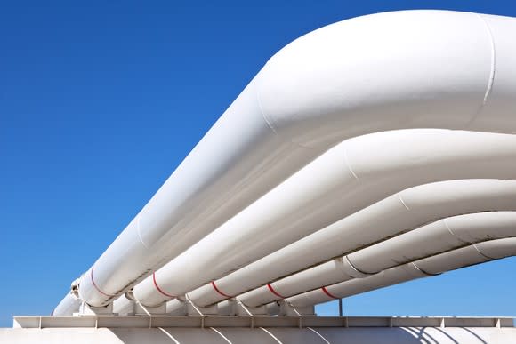 White gas pipelines with blue sky behind it.