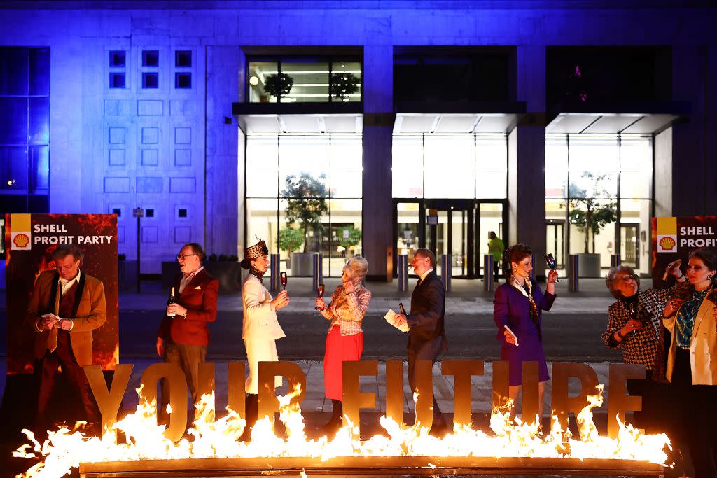  Greenpeace activists dressed as Shell board members hold a mock Shell profits party behind a burning sign reading "Your Future" during a protest outside Shell's headquarters in London on February 1, 2024, on the day that the oil and gas company releases its annual results. 