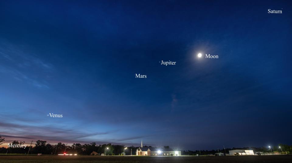 Five planets and the waning moon are strung across the eastern sky over Stedman Baptist Church in this photo made at dawn on June 20. Mercury was tough to spot on this morning as it appears very low at the lower left. Venus is the brightest planet visible followed by Jupiter. Mars appears between Venus and Jupiter. Saturn is at upper right.  In the coming days, Mercury will become even more difficult to spot and the moon will be absent from the dawn sky.