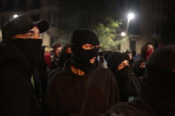 Protesters with their faces covered, look on in Barcelona, Spain, Thursday, Oct. 17, 2019. Catalonia's separatist leader vowed Thursday to hold a new vote to secede from Spain in less than two years as the embattled northeastern region grapples with a wave of violence that has tarnished a movement proud of its peaceful activism. (AP Photo/Joan Mateu)