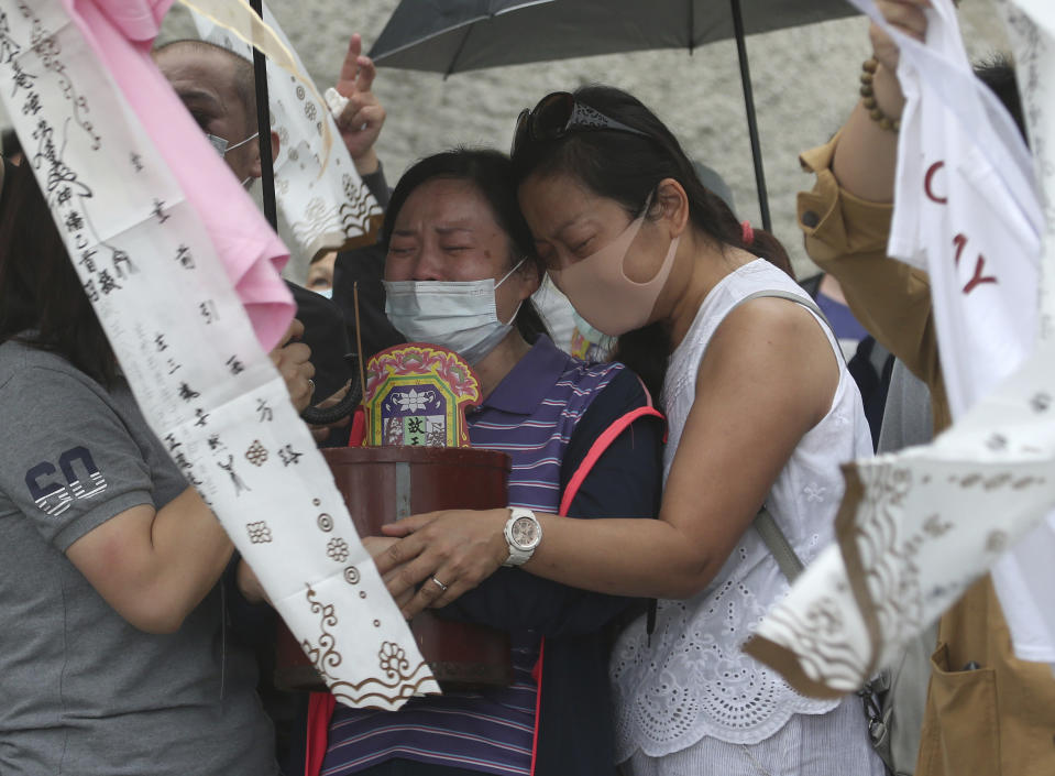 The families of the victims in a train crash try to conjure their spirits near Taroko Gorge in Hualien, Taiwan on Saturday, April 3, 2021. The train partially derailed in eastern Taiwan on Friday after colliding with an unmanned vehicle that had rolled down a hill, killing and injuring dozens. (AP Photo/Chiang Ying-ying)
