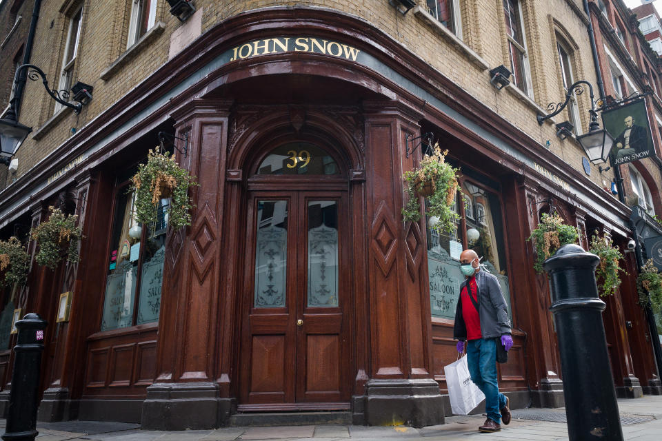 LONDON, ENGLAND - JUNE 19: A person wearing a protective face mask walks past a temporarily closed pub named after the founding father of epidemiology John Snow, on June 19, 2020 in London, England. Despite no guidelines coming from the government on how pubs, restaurants, hotels, and cafes should re-open, many are still pushing ahead to welcome customers back on July 4th 2020. The UK service industry went in to lockdown during the coronavirus pandemic on March 23rd 2020. (Photo by Leon Neal/Getty Images)