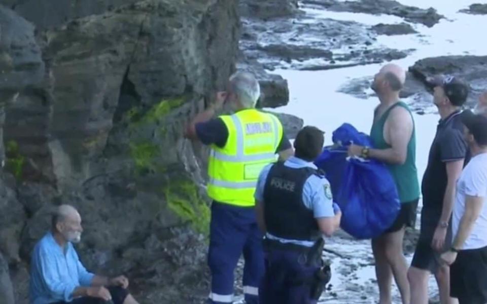Rescuers helped the nonagenarian walk across rocks to safety before he was taken to hospital - 9News
