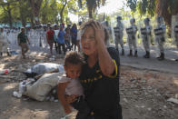 Una mujer que carga a su hijo se aleja de los miembros de la Guardia Nacional de México que bloquean el paso de un grupo de migrantes cerca de Tapachula, México, el jueves 23 de enero de 2020. (AP Foto/Marco Ugarte)