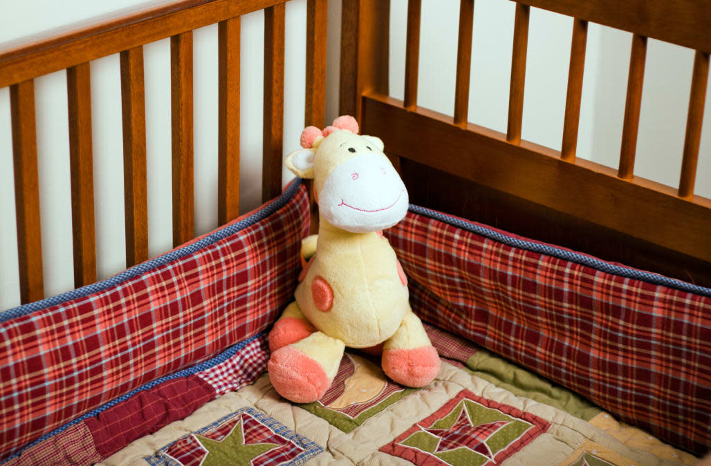 Yellow stuffed animal giraffe in empty baby crib