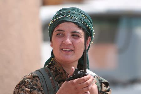 A female Kurdish fighter from the People's Protection Units (YPG) carries a walkie-talkie as she stands in the Ghwairan neighborhood of Hasaka, Syria, August 22, 2016. REUTERS/Rodi Said