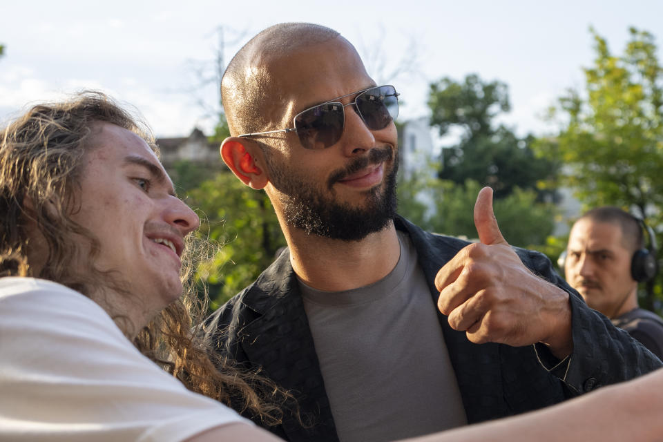 Andrew Tate gives a thumbs up while posing with a fan upon exiting the Court of Appeal in Bucharest, Romania, Thursday, July 6, 2023. Andrew Tate, the divisive social media personality and former professional kickboxer who is charged in Romania with rape, human trafficking, and forming a criminal gang to sexually exploit women, lost an appeal on Thursday against a court's earlier decision to keep him under house arrest, his spokesperson said. (AP Photo/Andreea Alexandru)