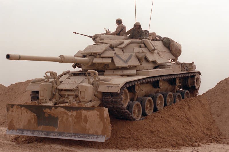 Marines from Company D, 2nd Tank Battalion, drive their M-60A1 main battle tank over a sand berm on Hill 231 on February 24, 1991, while rehearsing their role as part of the ground campaign in Kuwait during Operation Desert Storm. The tank is fitted with reactive armor and an M-9 bulldozer kit. File Photo by SSgt. M.D. Masters/U.S. Department of Defense