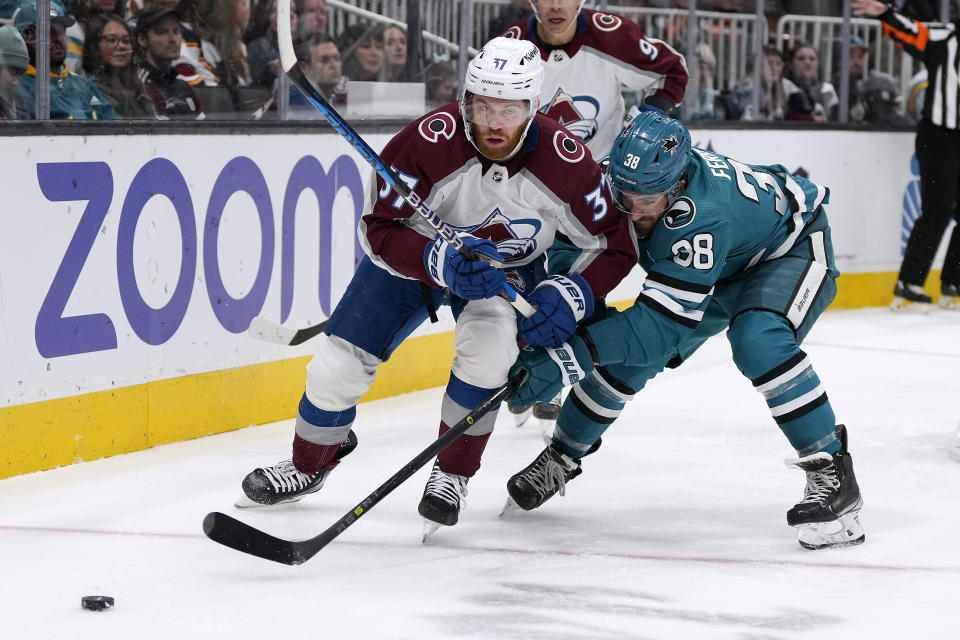 Colorado Avalanche left wing J.T. Compher (37) and San Jose Sharks defenseman Mario Ferraro (38) chase the puck in the second period of an NHL hockey game Tuesday, April 4, 2023, in San Jose, Calif. (AP Photo/Tony Avelar)