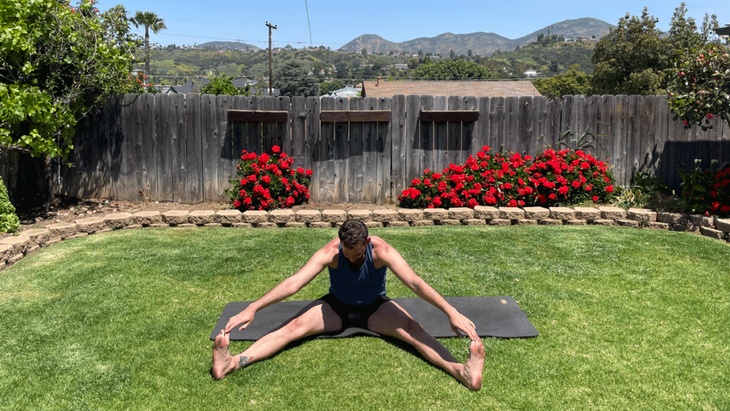 Man sitting on his yoga mat in his backyard practicing yoga for tall peoples