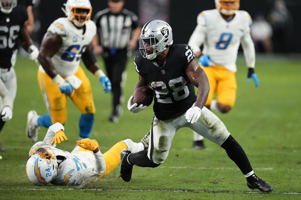 Las Vegas Raiders running back Josh Jacobs (28) carries past Los Angeles Chargers safety Nasir Adderley (24) during the second half of an NFL football game, Sunday, Dec. 4, 2022, in Las Vegas. (AP Photo/Matt York)