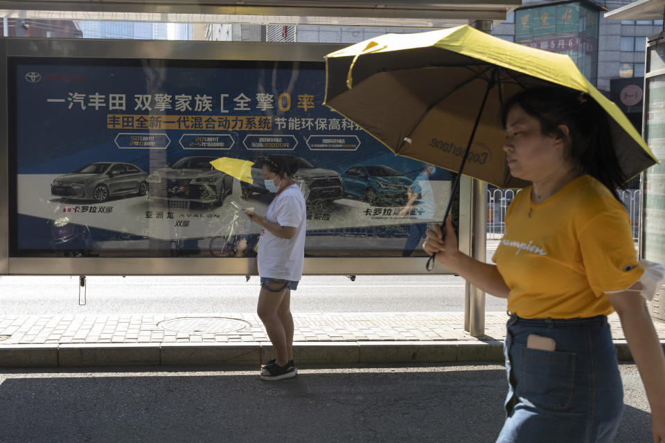 Residents pass by an advertisement for Hybrid cars from Toyota on the streets of Beijing on Tuesday, Aug. 4, 2020. China’s auto sales rose by 16.4% in July over a year earlier to 2.1 million units in a sign of sustained recovery for the industry’s biggest global market, an industry group said Tuesday. (AP Photo/Ng Han Guan)