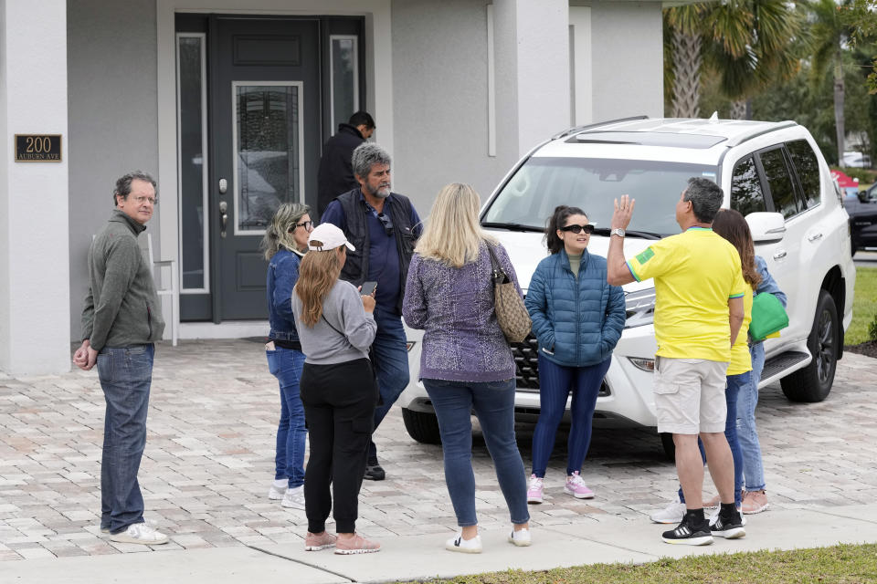 Supporters of former Brazilian president Jair Bolsonaro talk to a security guard asking for autographs from Bolsonaro outside the home where he is living Friday, Jan. 13, 2023, in Kissimmee, Fla. (AP Photo/John Raoux)