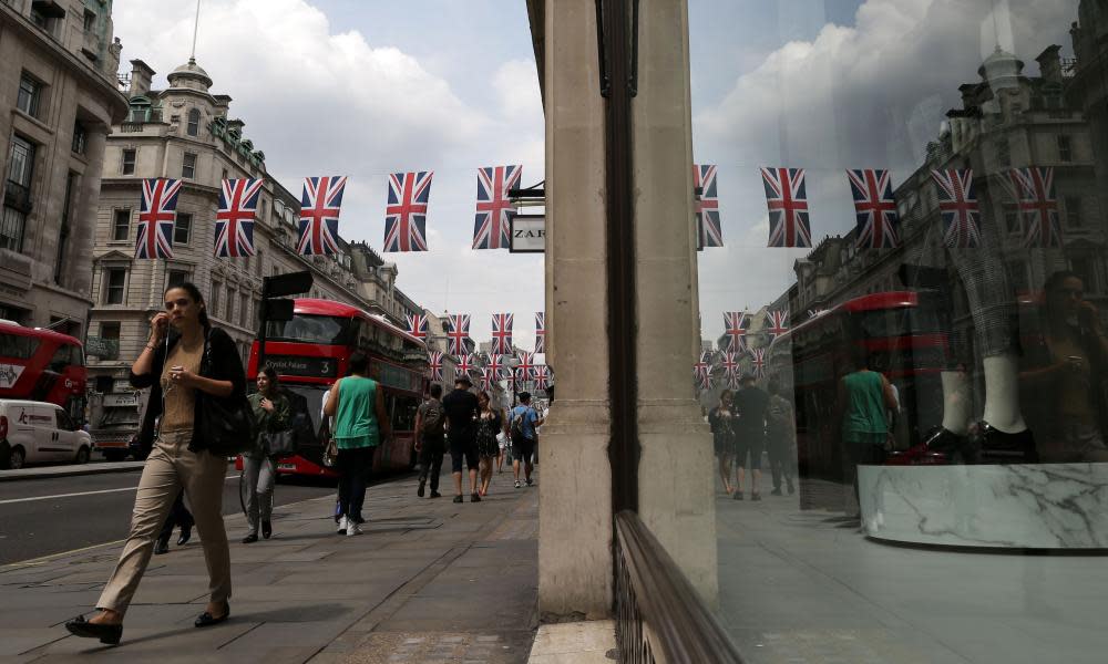 Shoppers walk under union flags hanging above Regent Street in central London