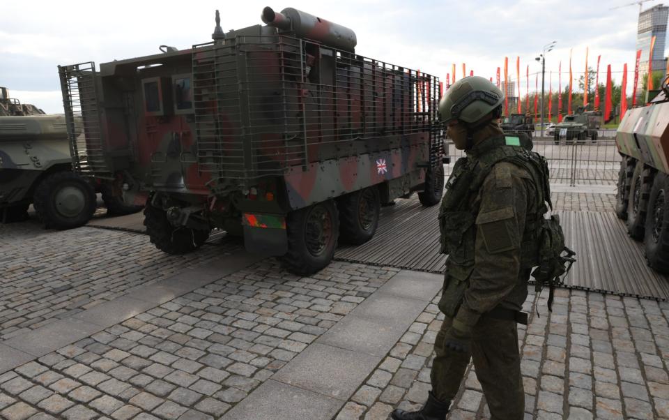 A Russian soldier looks at a British Mastiff armoured vehicle, which was captured in Ukraine