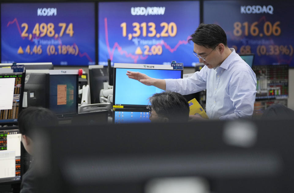 A currency trader gestures near the screens showing the Korea Composite Stock Price Index (KOSPI), left, and the foreign exchange rate between U.S. dollar and South Korean won, center, at the foreign exchange dealing room of the KEB Hana Bank headquarters in Seoul, South Korea, Wednesday, Dec. 6, 2023. Asian shares advanced on Wednesday after most stocks slipped on Wall Street following a mixed set of reports on the U.S. economy. (AP Photo/Ahn Young-joon)