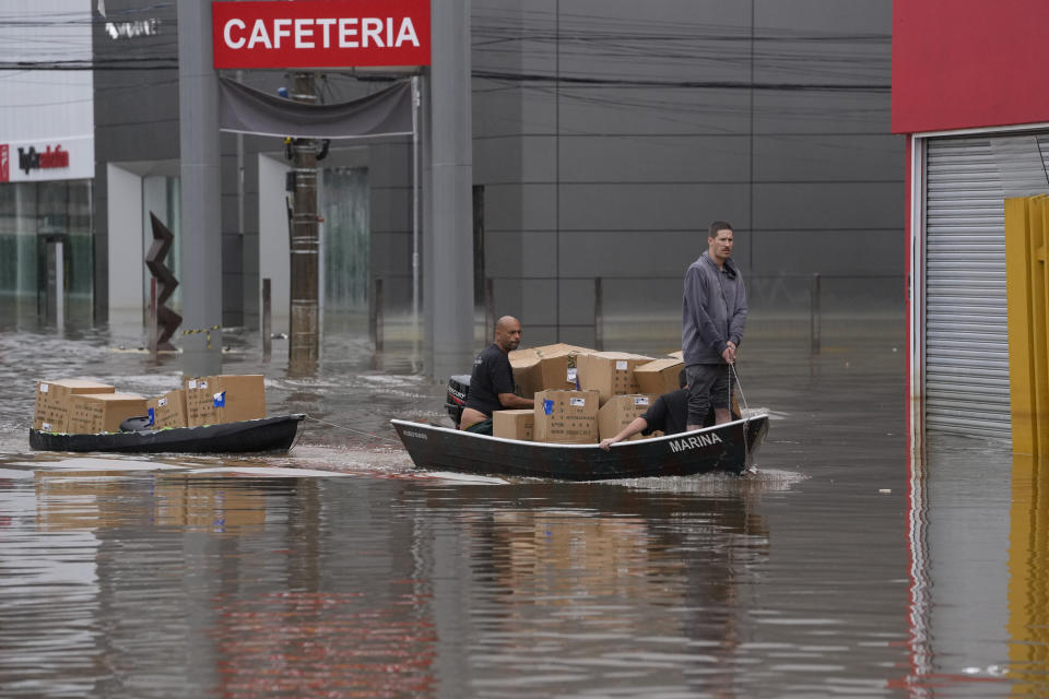 Volunteers transport donated supplies through a flooded street after heavy rains in Porto Alegre, Rio Grande do Sul state, Brazil, Sunday, May 12, 2024. (AP Photo/Andre Penner)