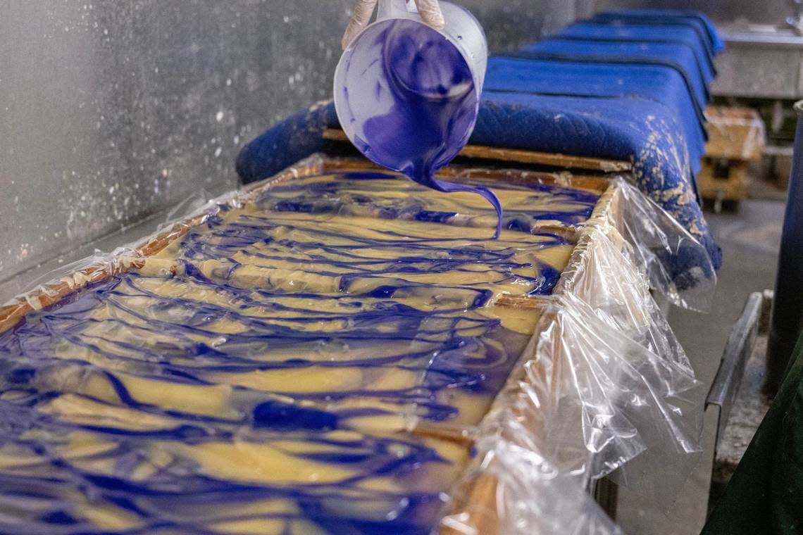 Purple mineral pigments, already mixed into a soap mixture, are poured into wooden trays to create the signature colors associated with the Zum Bar scents.