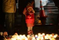 A young child points at candles as people pay their respects at a makeshift shrine to the victims of the Newtown school shooting, Connecticut, December 16, 2012. President Barack Obama has vowed to battle gun violence, casting the fight as a nation's duty to protect its young, as the Connecticut town of Newtown prepared to bury the first two victims of last week's rampage at an elementary school