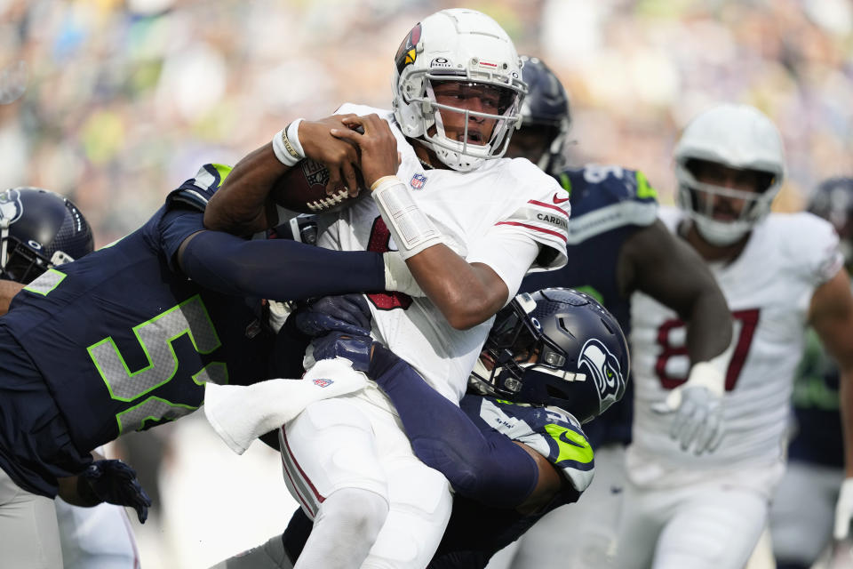 Arizona Cardinals quarterback Joshua Dobbs, center, gets tackled by Seattle Seahawks linebackers Jordyn Brooks, right, and Darrell Taylor, left, during the second half of an NFL football game Sunday, Oct. 22, 2023, in Seattle. (AP Photo/Lindsey Wasson)