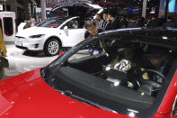 In this April 17, 2019, photo, attendees take a look at electric cars from Tesla at the Auto Shanghai 2019 show in Shanghai. China's electric car sales are stalling following the end of multibillion-dollar subsidies that made it the biggest market for the technology. Communist leaders want to make China a leader in electric cars but are shifting the burden to the industry by imposing mandatory sales quotas. (AP Photo/Ng Han Guan)