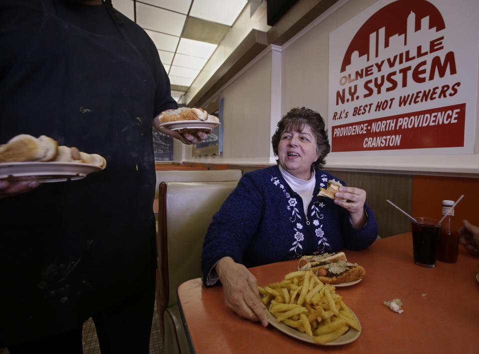 In this Monday, March 3, 2014 photo, waiter/cook Nicholas Barros delivers orders to the table of Judy Dexter at Olneyville New York System of Providence in Providence, R.I. The James Beard Foundation named the Rhode Island restaurant one of five "American Classics". (AP Photo/Stephan Savoia)