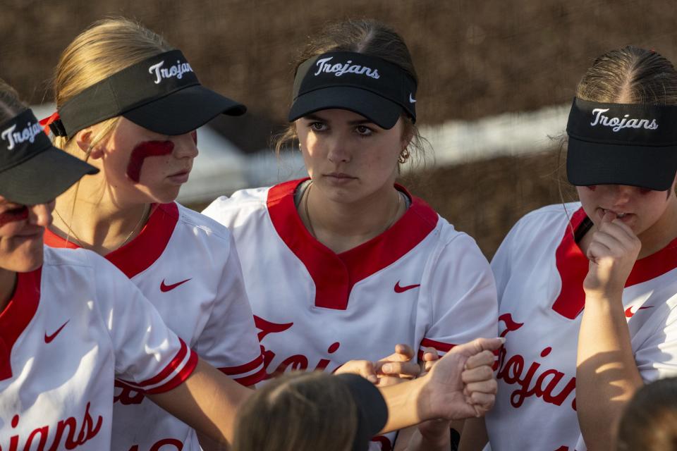 Center Grove High School senior Riley Henson, center, gathers with her teammates between innings during an IHSAA softball game against Pendleton Heights High School, Friday, March 29, 2024. Host Center Grove won, 7-6.