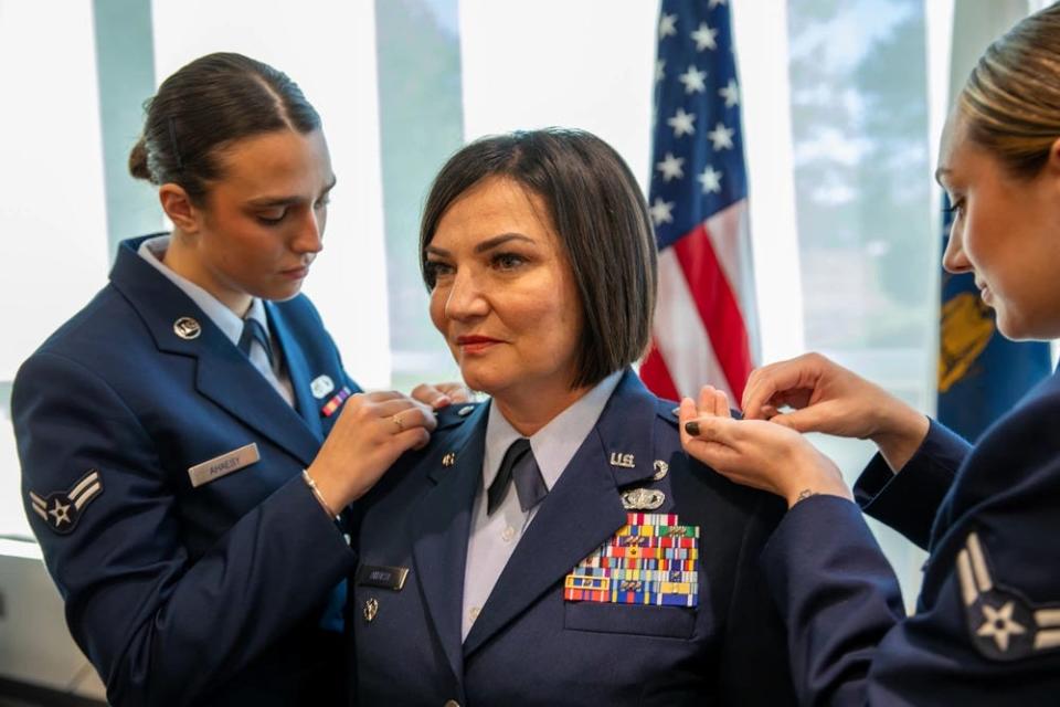 Airman 1st Class Laura Kate Ahaesy and Airman 1st Class Julia Ahaesy, pin the rank of brigadier general on their mother, newly promoted Brig. Gen. Lisa Ahaesy, during her promotion ceremony at the Massachusetts National Guard Joint Forces Headquarters at Hanscom Air Force Base on Dec. 12, 2023.