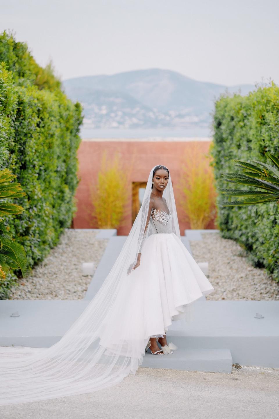 A bride poses in her wedding dress in front of a mountain.