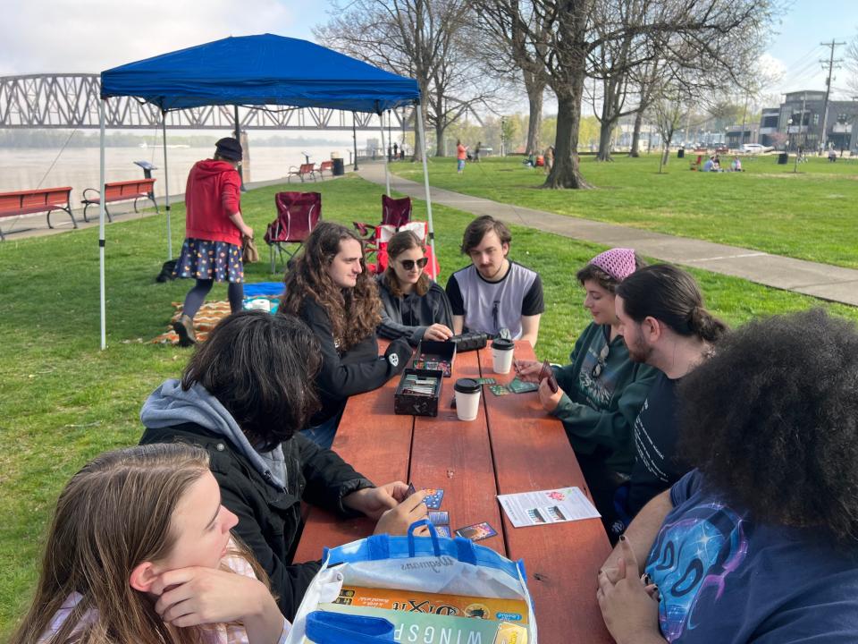 Nine 20-somethings from Maryland play Dungeons Mayhem card game Monday morning beside their tent in Downtown Henderson’s Audubon Mill Park some four hours before the solar eclipse goes into totality.