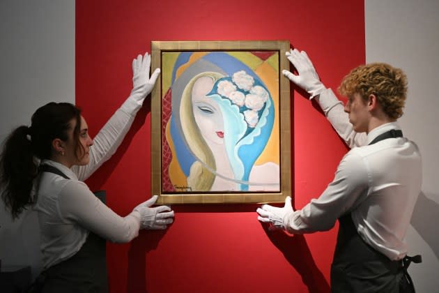 Gallery assistants pose with the original artwork by E. Frandsen De Schomberg used for the cover of Derek and The Dominos album 'Layla and Other Assorted Love Songs' - Credit: Justin Tallis/AFP via Getty Images