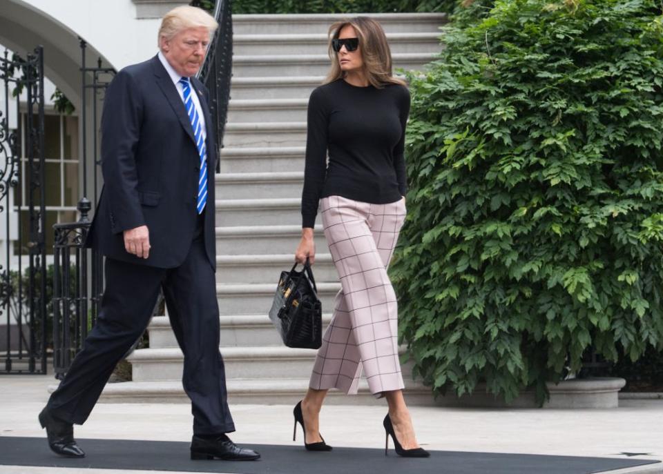 <p>Melania Trump wore plaid Valentino trousers for the first day of her second international trip with the president. She carried with her a crocodile-skinned Birkin bag (<a rel="nofollow noopener" href="https://www.townandcountrymag.com/style/fashion-trends/a9956043/birkin-bag-auction-hong-kong/" target="_blank" data-ylk="slk:a iconic style;elm:context_link;itc:0;sec:content-canvas" class="link ">a iconic style</a>), and a pair of black visor sunglasses to match. </p>