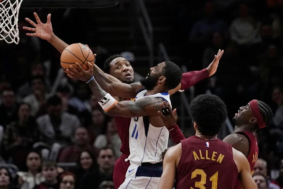 Mavericks guard Kyrie Irving, center, goes to the basket between Cavaliers guard Donovan Mitchell, left, center Jarrett Allen (31) and guard Caris LeVert, right, during the second half, Tuesday, Feb. 27, 2024, in Cleveland.
