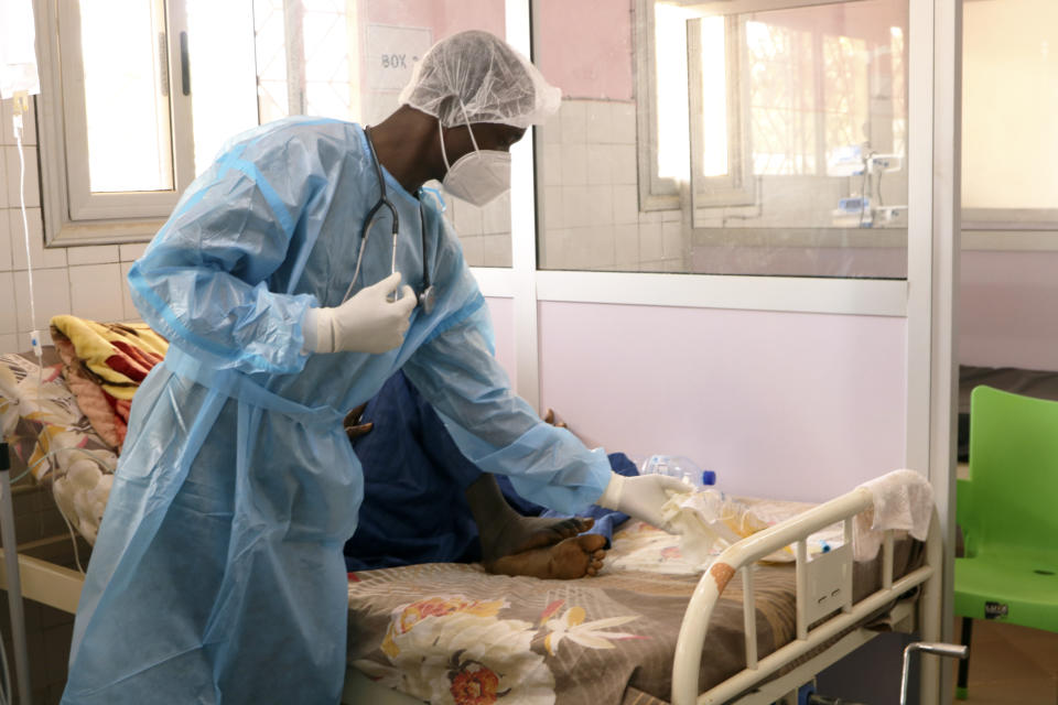 Dr. Dieudonne Wend-Kuni Kientega tends to a COVID-19 patient at Ouagadougou's Bogodogo Medical Teaching Hospital Thursday Feb. 4, 2021. Since November, the conflict-riddled West African nation of Burkina Faso faces a much deadlier second coronavirus wave than the first and health officials worry a lack of knowledge and adherence to coronavirus measures is making it hard to rein in. (AP Photo/Sam Mednick)