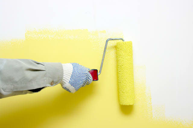 hand painting a white wall with ...