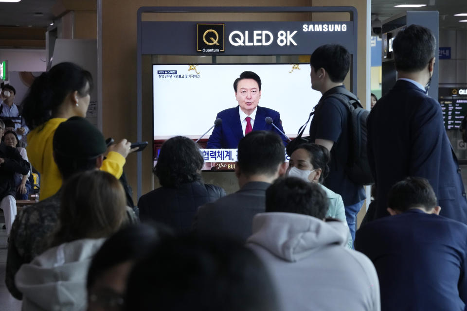 People watch a TV screen showing the live broadcast of South Korean President Yoon Suk Yeol's press conference, at the Seoul Railway Station in Seoul, South Korea, Thursday, May 9, 2024. (AP Photo/Ahn Young-joon)