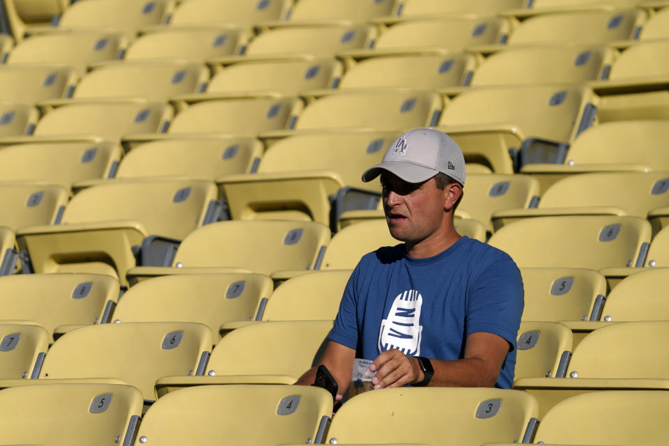 A fan wears a shirt for Vin Scully before a ceremony to honor the memory of the Los Angeles Dodgers announcer prior to a baseball game between the Dodgers and the San Diego Padres Friday, Aug. 5, 2022, in Los Angeles. Scully, the Hall of Fame broadcaster, whose dulcet tones provided the soundtrack of summer while entertaining and informing Dodgers fans in Brooklyn and Los Angeles for 67 years, died Tuesday night. (AP Photo/Mark J. Terrill)