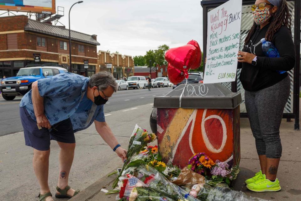 A protester puts flowers in front of the memorial of George Floyd (AFP via Getty Images)