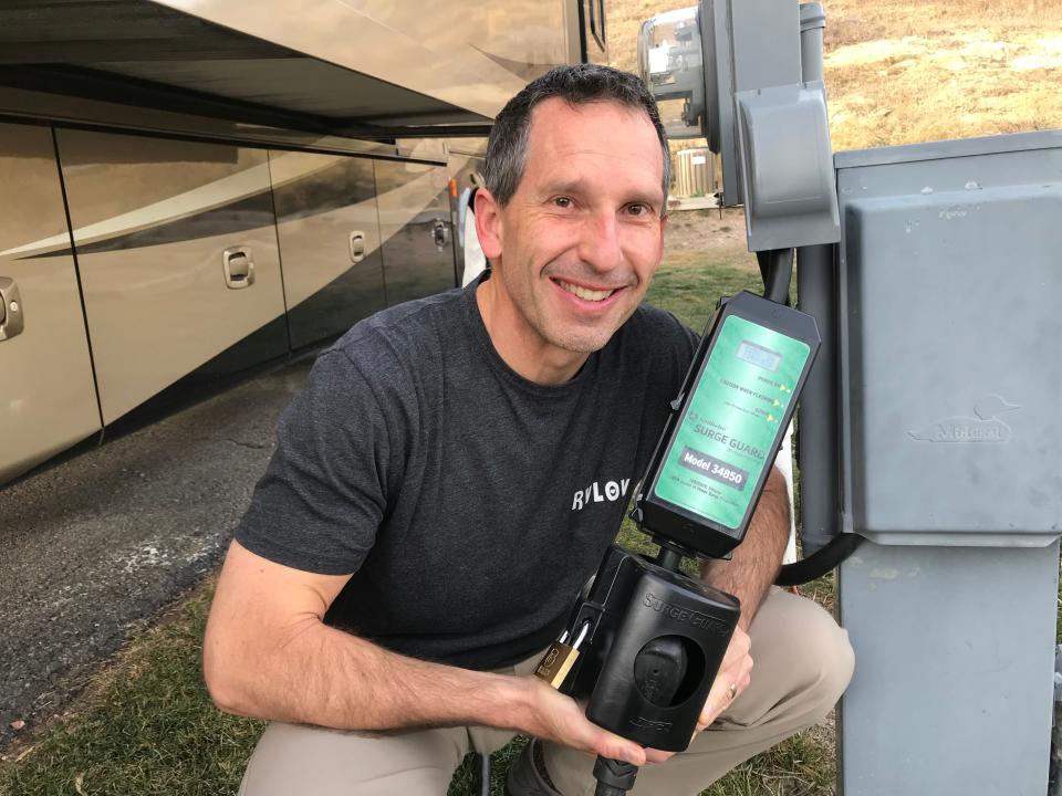 Marc holds the surge guard between the RV and power source