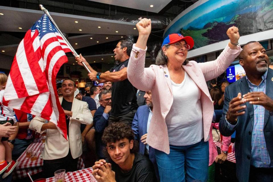 La alcaldesa del Condado Miami-Dade Daniella Levine Cava (al centro) y el alcalde de Miami Francis Suárez (detrás a la izquierda) reaccionando junto con el alcalde de Miami Gardens Rodney Harris (a la derecha) y los fans al fútbol reunidos al ser Miami seleccionada como una de las ciudades sede de la Copa Mundial de la FIFA 2026 durante una fiesta de observación en Fritz and Franz Bierhaus en Coral Gables, la Florida, el jueves 16 de junio de 2022.