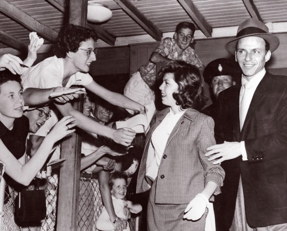 Eager fans almost spill over the fence in their efforts to get autographs from Nancy and her father, Frank Sinatra (1955)AFP via Getty