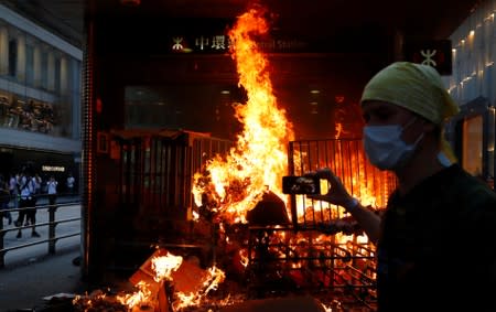 A protester films a fire at the entrance of MTR Central Station in Hong Kong