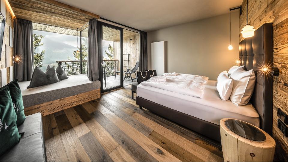 An interior shot of a standard room at the My Arbor treetop hotel in the Dolomites, with a view of the mountains out the window