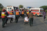 In this handout photo released by Punjab Province's Emergency Service Rescue 11222, shows rescue workers removing bodies at the site of a deadly bus accident near Dera Ghazi Khan, Pakistan, Monday, July 19, 2021. The speeding bus carrying mostly laborers traveling home for a major Muslim holiday rammed into a container truck on a busy highway in central Pakistan, killing and injuring dozens, police and rescue officials said. (Emergency Service Rescue 1122 via AP)