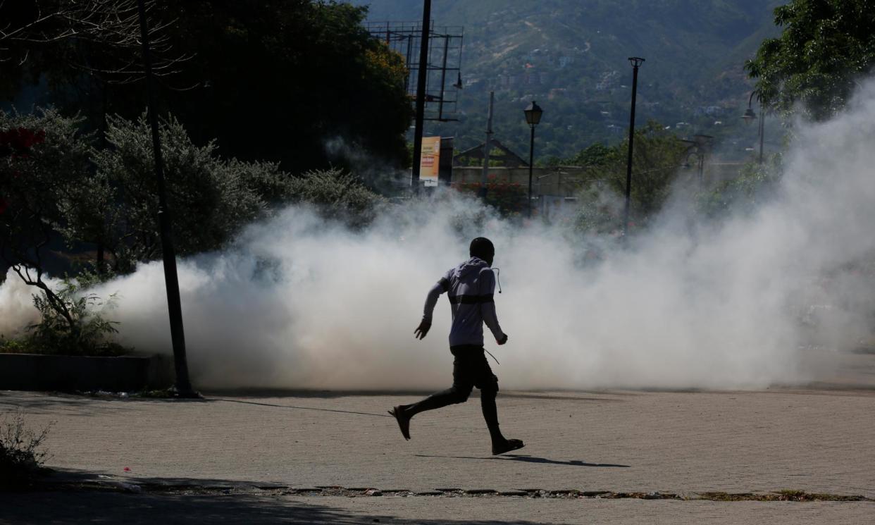 <span>A man runs for cover as riot police launch teargas in an effort to remove street vendors in the Champs de Mars area in Port-au-Prince, Haiti, on Tuesday.</span><span>Photograph: Odelyn Joseph/AP</span>